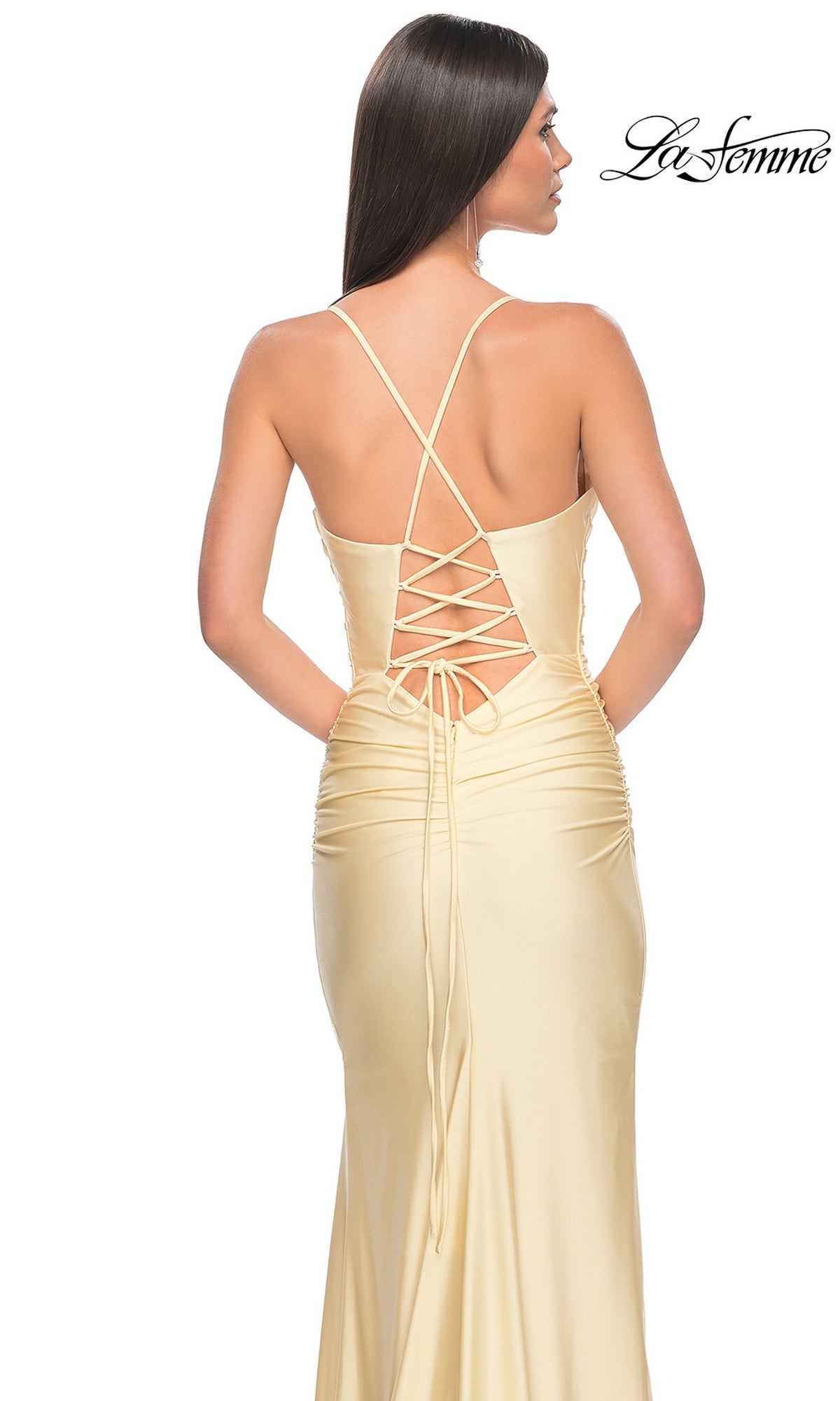 Woman in a light yellow satin La Femme Corset-Back Long Prom Dress 31131 with crisscross straps, posing against a white background. The La Femme logo appears in the top right corner.